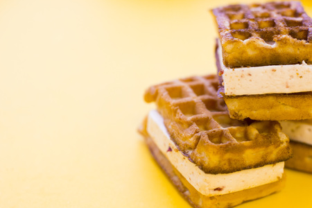 Delicious breakfast: fresh waffles on a yellow background with copy spaceの写真素材