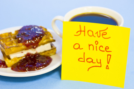 Delicious breakfast: a plate of fresh waffles with raspberry jam, a cup of coffee and Have a Nice Day yellow sticker note on a blue background with copy spaceの写真素材