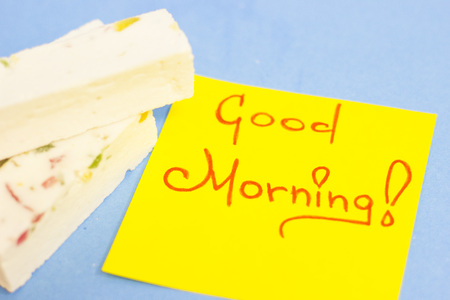 Pieces of vanilla fudge with fruit and Good Morning yellow sticker note on a blue backgroundの写真素材