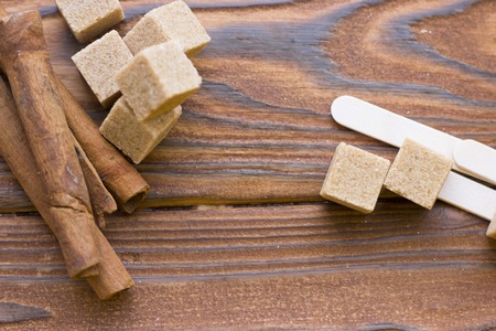 Dark natural wooden background with spa essentials: cinnamon sticks and brown sugar cubes, top viewの写真素材