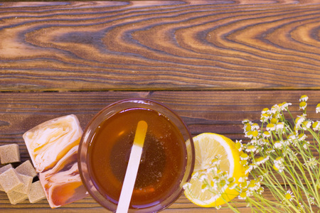 Set of sugaring essentials a bowl of honey, lemon, a bar of fruit soap and brown sugar on a natural dark wooden background, top viewの写真素材
