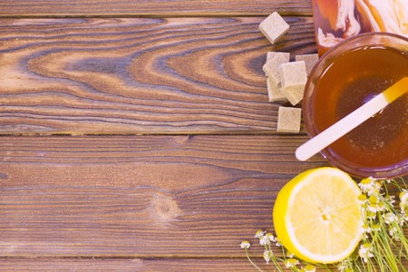 Set of sugaring essentials a bowl of honey, lemon, a bar of fruit soap and brown sugar on a natural dark wooden background, top viewの写真素材