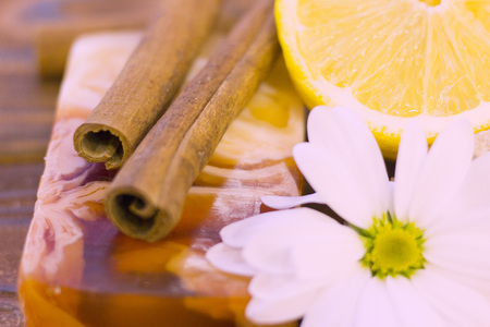 A close up of spa essentials with fruit soap, lemon and cinnamon sticks on a natural dark wooden backgroundの写真素材