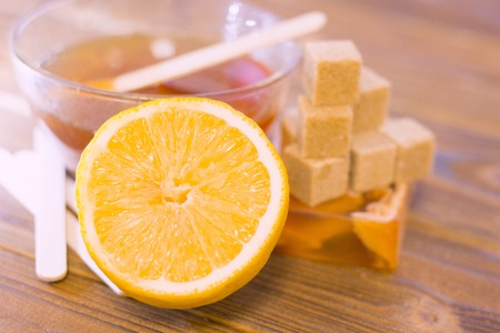 A close up of spa essentials with fruit soap, a bowl of honey, brown sugar and lemon on a natural dark wooden backgroundの写真素材