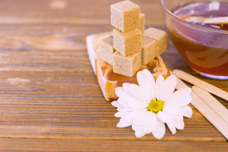 A set of spa essentials with fruit soap, a bowl of honey, brown sugar and camomile on a natural dark wooden backgroundの写真素材