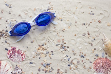 Enjoying vacation mood, swimming glasses on white sand background. Space for a text or product display, top view.の写真素材