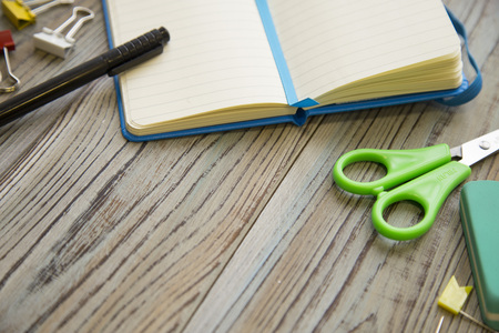 A set of school supplies with notebook and scissors, grey wooden background, copy spase