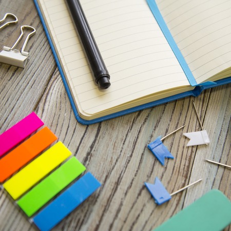 A set of school supplies with notebook and scissors, grey wooden background, close up, copy spase