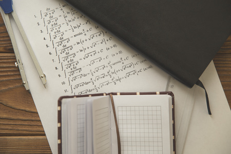 Studying Math with formulas, a pair of compasses and black planner on dark wooden background, top viewの写真素材