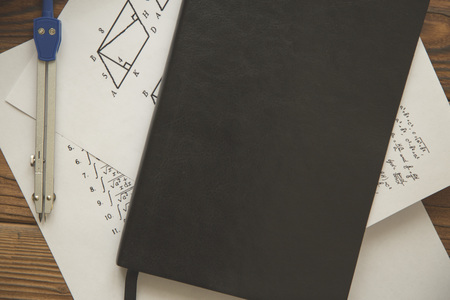 Studying Math with formulas, a pair of compasses and black planner on dark wooden background, top...