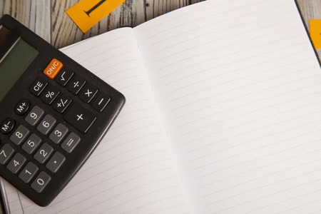 An opened blank notebook and a calculator on a grey wooden background, top view, close up,copy spaceの写真素材