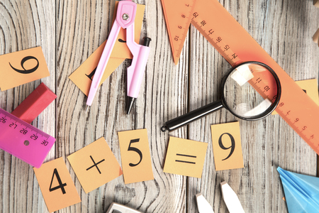 Pink and orange rulers, magnifying glass and numbers on a grey wooden background, top view, copy spaceの写真素材