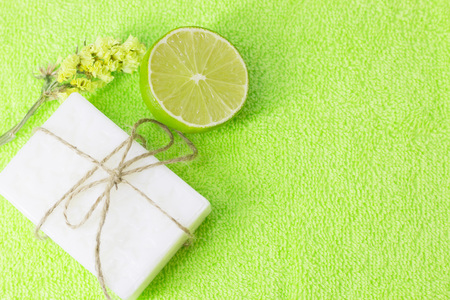Fruit aromatherapy spa concept with flower, soap bar and lime mock up, green background, closupの写真素材