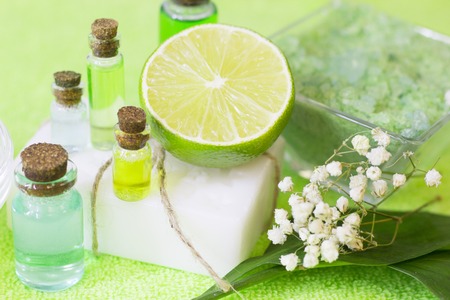 Fruit aromatherapy spa concept with essential oil in glass bottles, soap bars, jelly lotion and lime mock up, green background, closupの写真素材