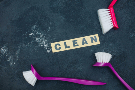 Cleaning house or office concept. Red and purple cleaning brushes, CLEAN inscription on a dark concrete background. Closeupの写真素材