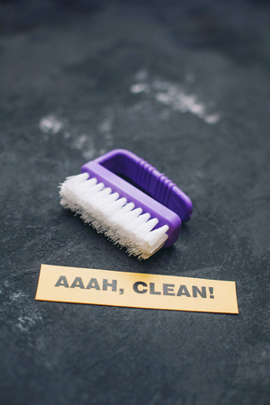 Cleaning house or office concept. Purple cleaning brush, AAAH, CLEAN inscription on a dark concrete background. Top view, closeupの写真素材