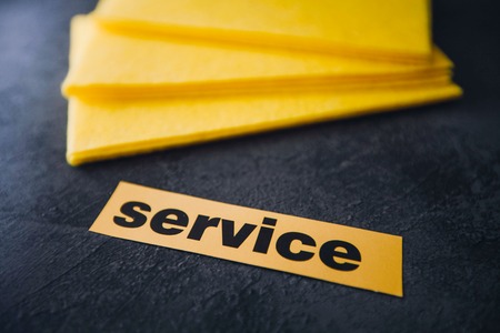 Cleaning house or office concept. Yellow cleaning rag, Service inscription on a dark concrete background. Top view, closeupの写真素材