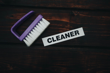 Cleaning house or office concept. Purple cleaning brush, CLEANER inscription on a dark wooden background. Top view, closeupの写真素材