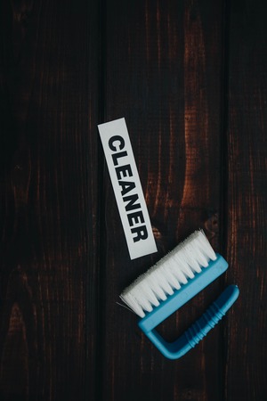 Cleaning house or office concept. Blue cleaning brush, CLEANER inscription on a dark wooden background. Top view, closeupの写真素材