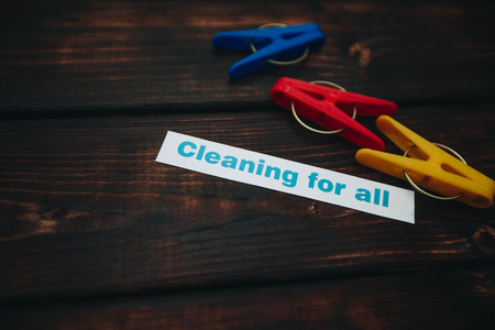 Cleaning house or office concept. Colorful clothes pegs, Cleaning for all inscription on a dark wooden background. Top view, closeupの写真素材