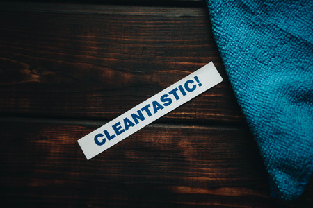 Cleaning house or office concept. Blue cleaning rag, Cleantastic inscription on a dark wooden background. Top view, closeupの写真素材