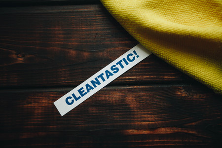 Cleaning house or office concept. Yellow cleaning rag, Cleantastic inscription on a dark wooden background. Top view, closeupの写真素材