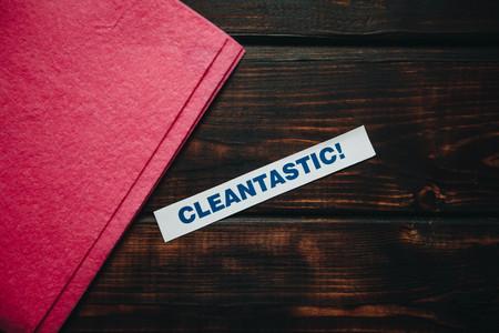 Cleaning house or office concept. Red cleaning rag, Cleantastic inscription on a dark wooden background. Top view, closeupの写真素材