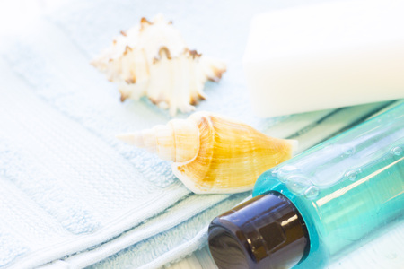 Spa items set with a blue bottle of showel gel, a bar of soap, sea shells and towels, close up, white backgroundの写真素材