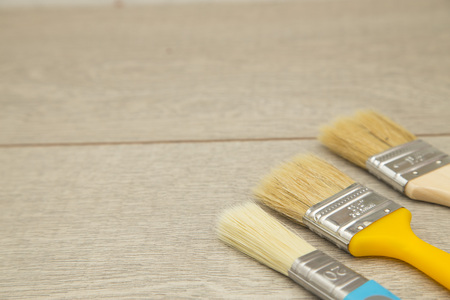 Repair, Redecorating Concept.A set of wooden and plastic paint brushes on a light wooden table,...