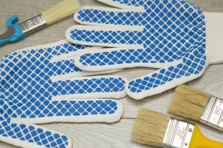 Repair, Redecorating Concept. Paint brushes and a pair of protective work gloves on a light wooden background, close upの写真素材