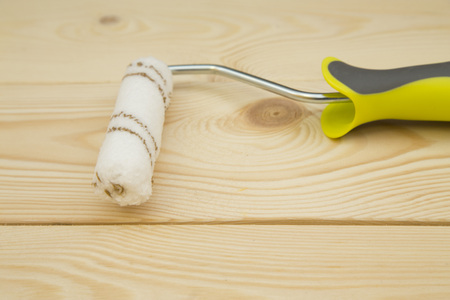 Repair, Redecorating Concept. A paint roller on a light uncolored wooden background, close up