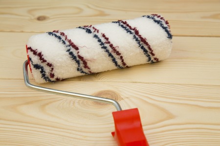 Repair, Redecorating Concept. A paint roller on a light uncolored wooden background, close up