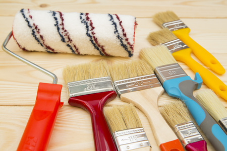 Repair, Redecorating Concept. A set of paint brushes and a paint roller on a light uncolored wooden...