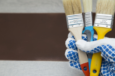 Repair, Redecorating Concept.Man's hand in protective glove is holding a set of paint brushes, dark wooden backgroundclose up, top viewの写真素材