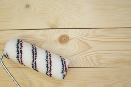 Repair, Redecorating Concept. A paint roller on a light uncolored wooden background with copy space,...