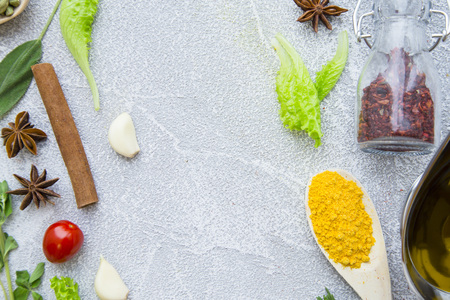 Dry spices and herbs in a wooden spoon and glass jar, fresh herbs olive oil and cinnamon stick on a...