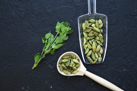 Dry beans in a glass and wooden spoon and glass jar ,fresh herbs on a black stone background with copy space, top viewの写真素材