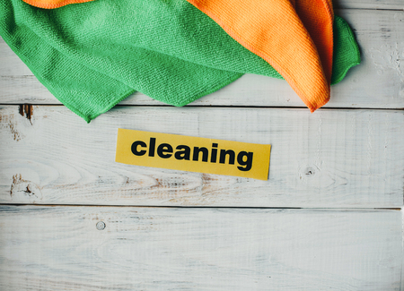 Keep your house clean and healthy with a fluffy yellow and green cotton mop. Contrast composition of cleaning tools, white wooden background. Top view.の写真素材