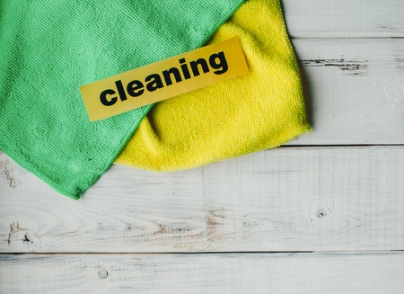 Keep your house clean and healthy with a fluffy yellow and green cotton mop. Contrast composition of cleaning tools, white wooden background. Top view.の写真素材