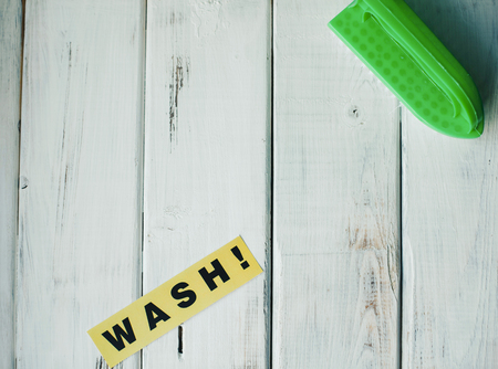 Cleaning house or office concept. Green cleaning brush and WASH inscription on a white wooden background. Top view, closeupの写真素材