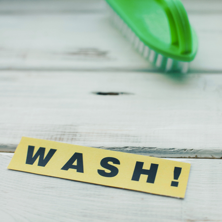 Cleaning house or office concept. Green cleaning brush and WASH inscription on a white wooden background. Top view, closeupの写真素材