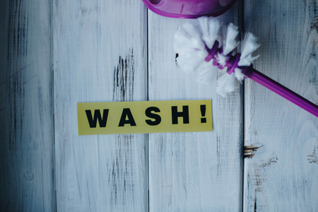 Cleaning house or office concept. Pink toilet cleaning brush and WASH inscription on a white wooden background. Top view, closeupの写真素材