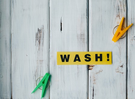 Wash inscription and colorful clothes pegs on a white wooden backgroundの写真素材