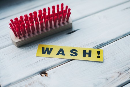 Cleaning house or office concept. Red cleaning brush and WASH inscription on a white wooden background. Top view, closeupの写真素材