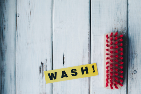 Cleaning house or office concept. Red cleaning brush and WASH inscription on a white wooden background. Top view, closeupの写真素材