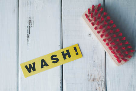 Cleaning house or office concept. Red cleaning brush and WASH inscription on a white wooden background. Top view, closeupの写真素材