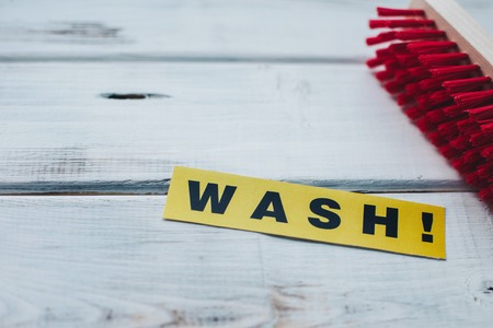 Cleaning house or office concept. Red cleaning brush and WASH inscription on a white wooden background. Top view, closeupの写真素材