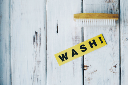 Cleaning house or office concept. Wooden cleaning brush and WASH inscription on a white wooden background. Top view, closeupの写真素材