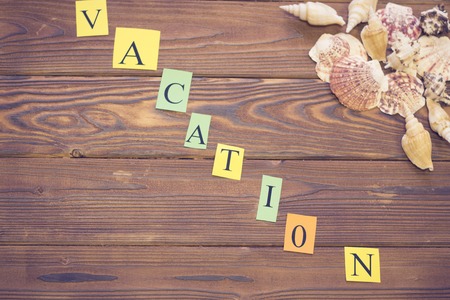 Get ready for vacation. Vacation inscription with sea shells hearts on a wooden table, top view, copy spaceの写真素材