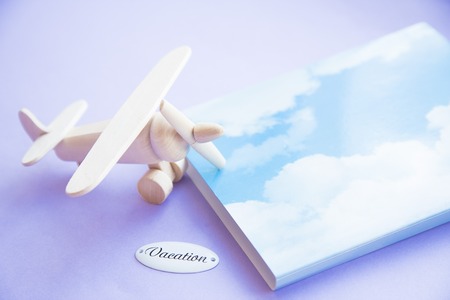 Vacation concept. Toy airplane and notepad on blue flat background, top view, flat layの写真素材